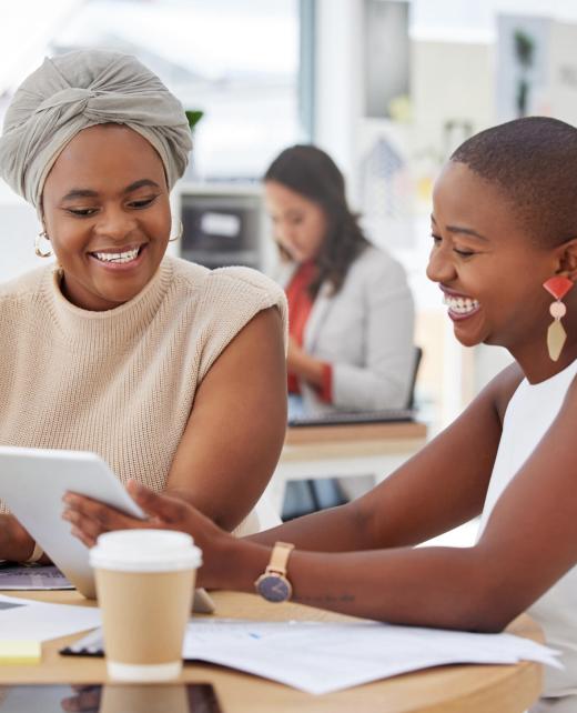 Smiling african american business women sitting together and using a digital tablet during a brains.